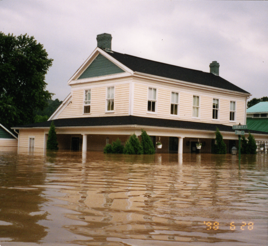 A large white house submerged in feet of water during a flood.