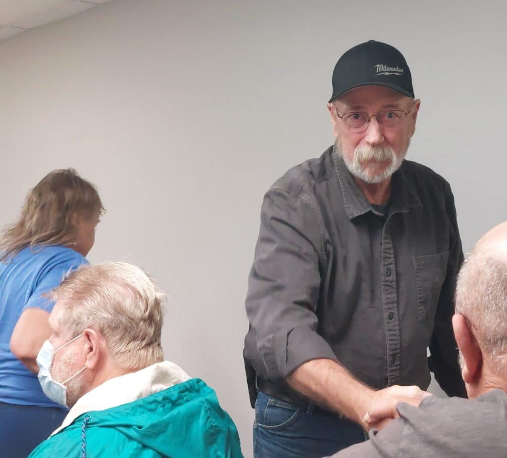 Mark Hall Sr. shakes hands with an audience member in the foreground.