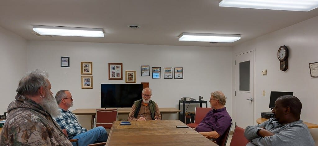 Four members of Amesville Village Council and the mayor sit talking inside village hall.