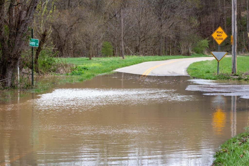 flood water near a "road may flood" sign on harmony road
