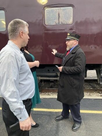 Two men stand before a train.