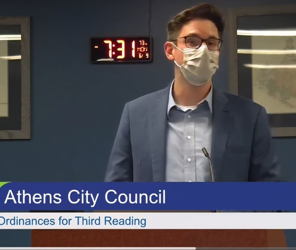 Man in mask speaking before a podium