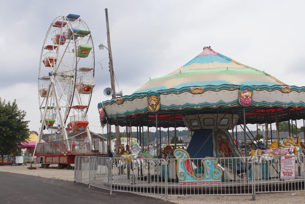 A carousel and a Ferris wheel at the fairgrounds.