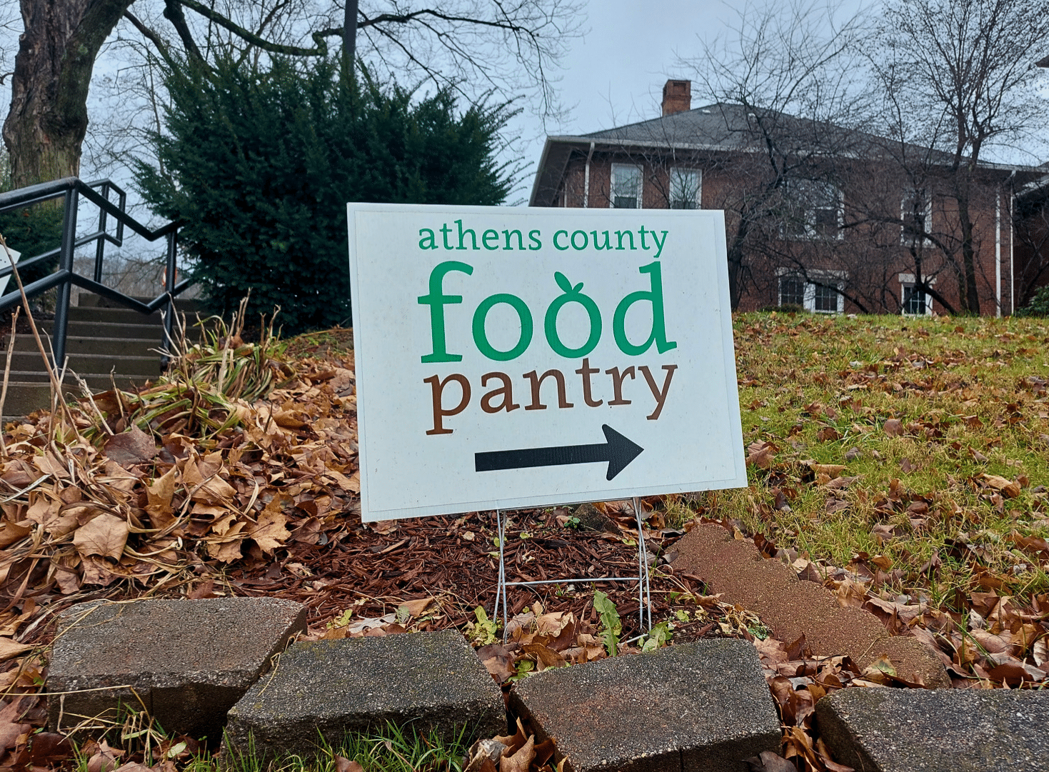 A sign for the Athens County Food Pantry in the foreground; in the background, Athens County Jobs & Family Services in Millfield.
