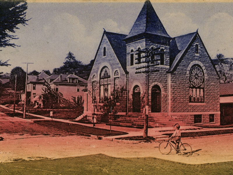An antique postcard depicting the Mount Zion Baptist Church in Athens, Ohio, with a child on a bicycle in the foreground