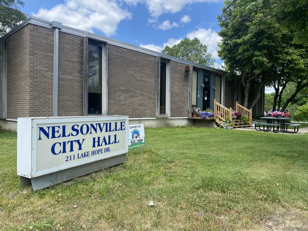 A sign for Nelsonville City Hall, and the building's exterior.