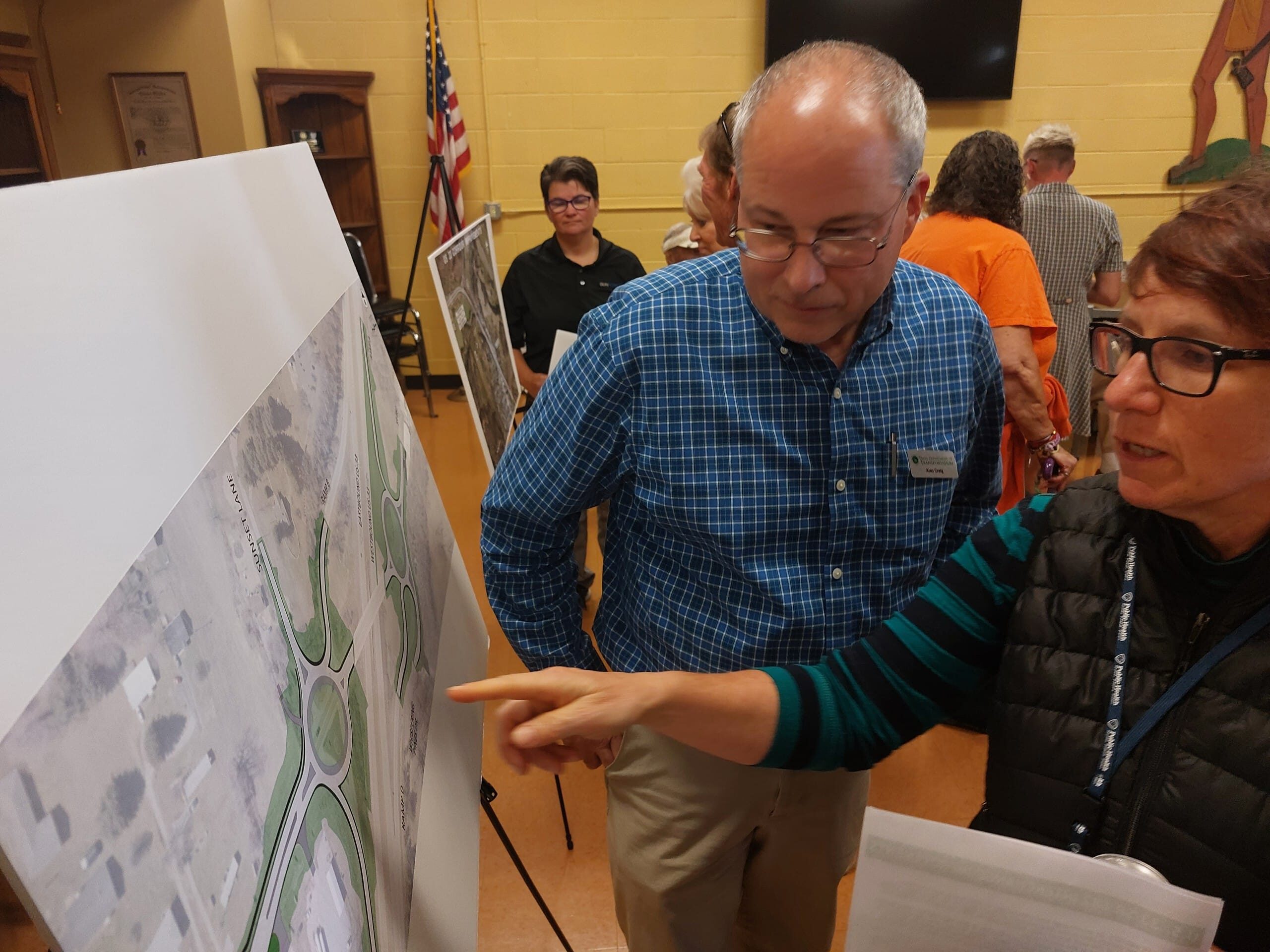 A man listens intently while a woman points and talks about certain areas of a map.