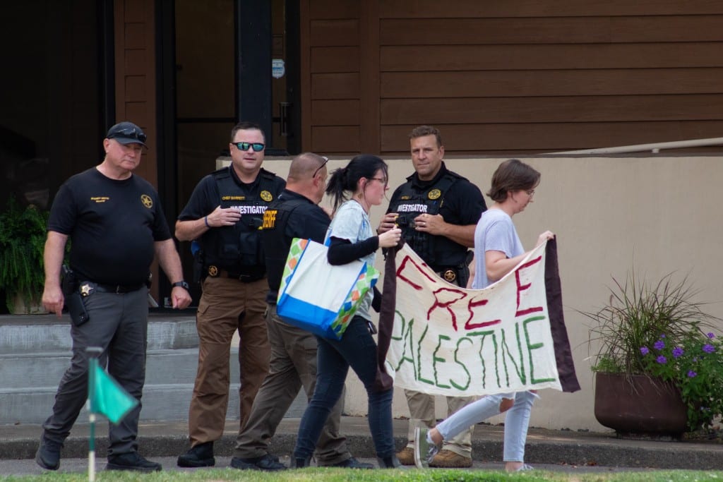 Protestors leave the country club entrance, per direction of law enforcement.