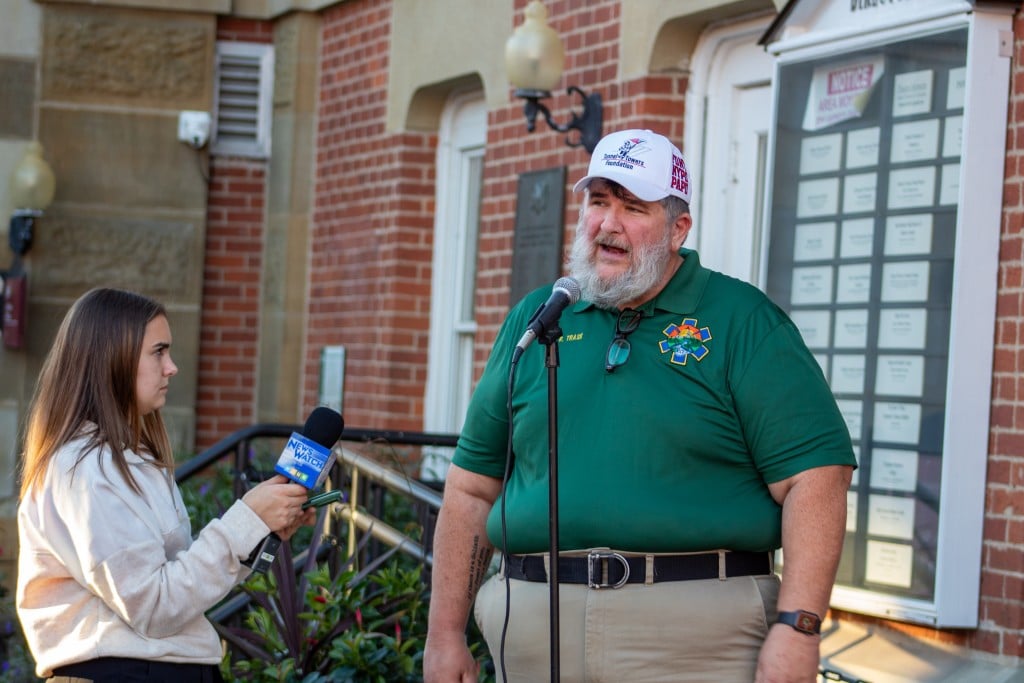 A man stands behind a microphone, speaking.