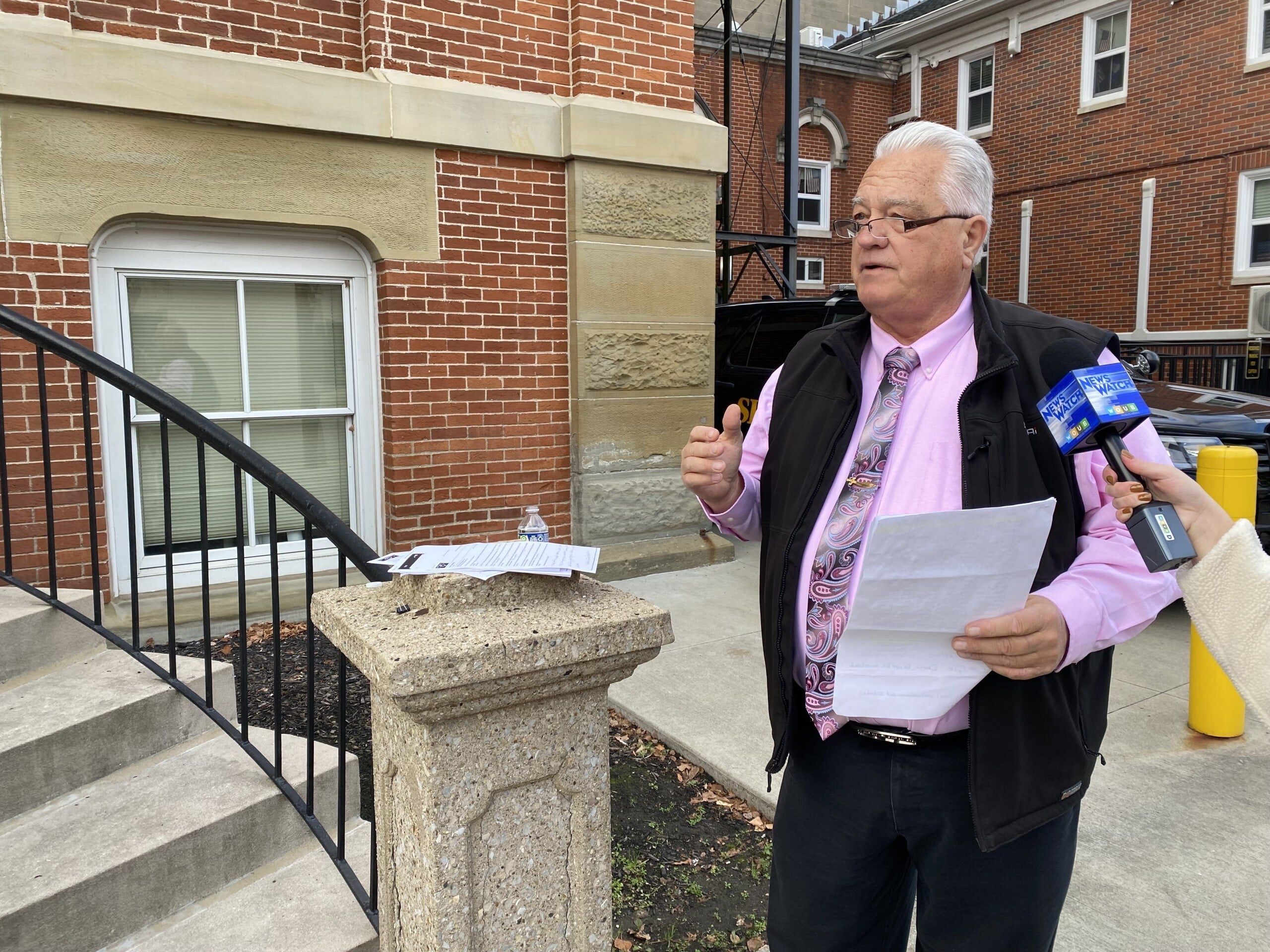 man holding papers in front of building