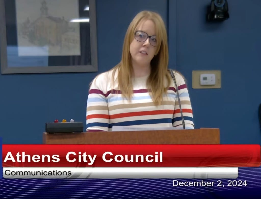 A woman stands before a microphone.