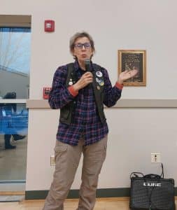 Barbara Stout speaks, holding a micrphone.