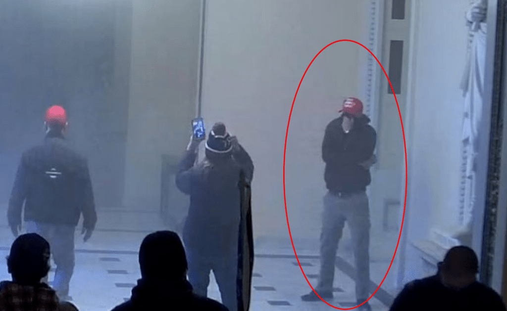 A man covers his face as a room fills with tear gas.