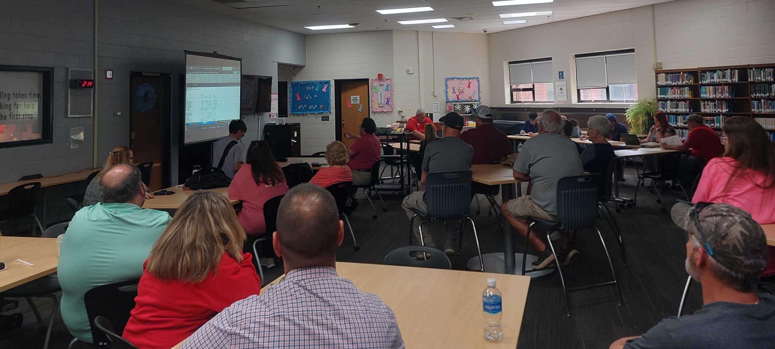 People sit in a school library watching a presentation.