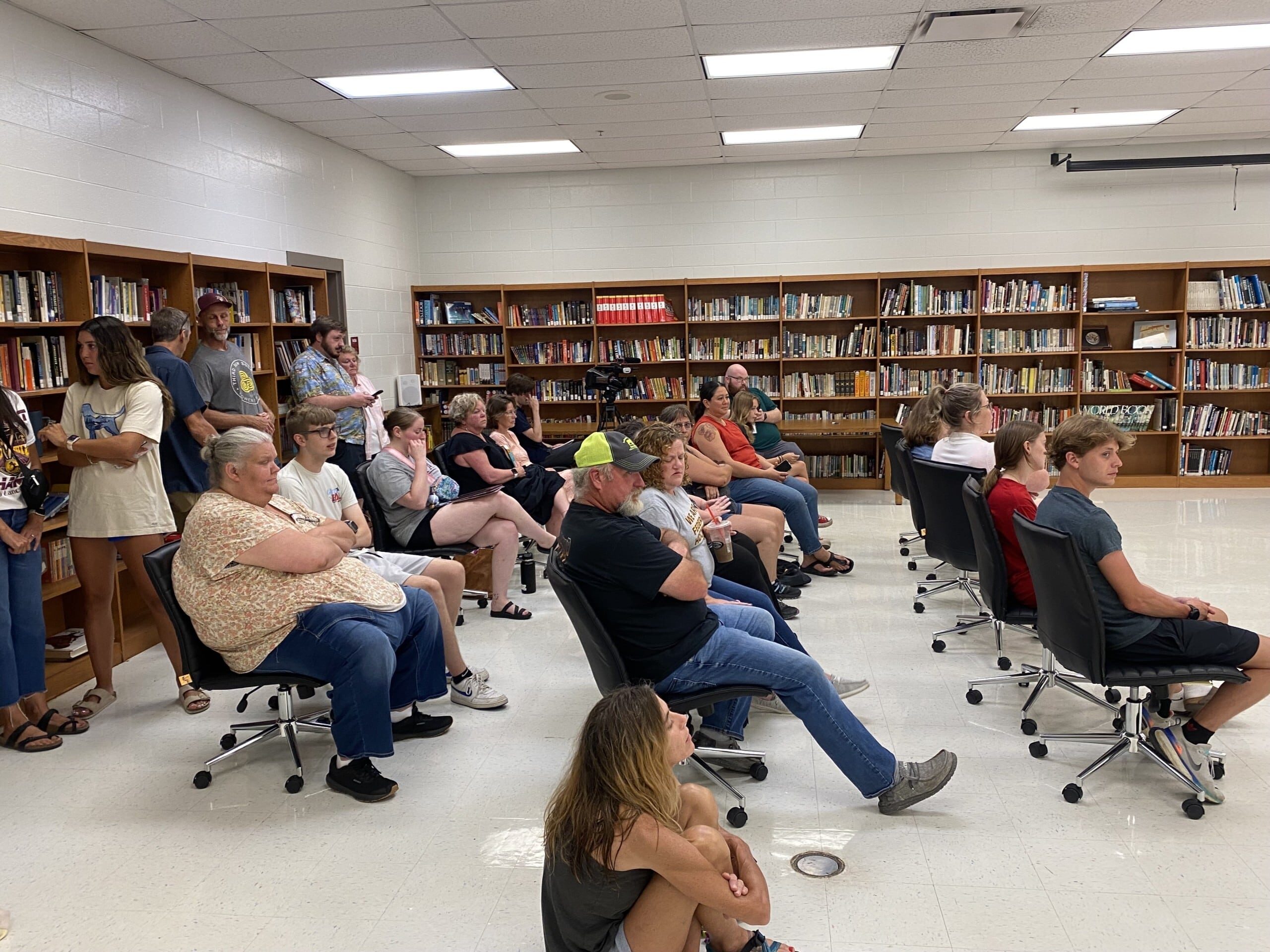 Group of people sitting in chairs and on the floor.
