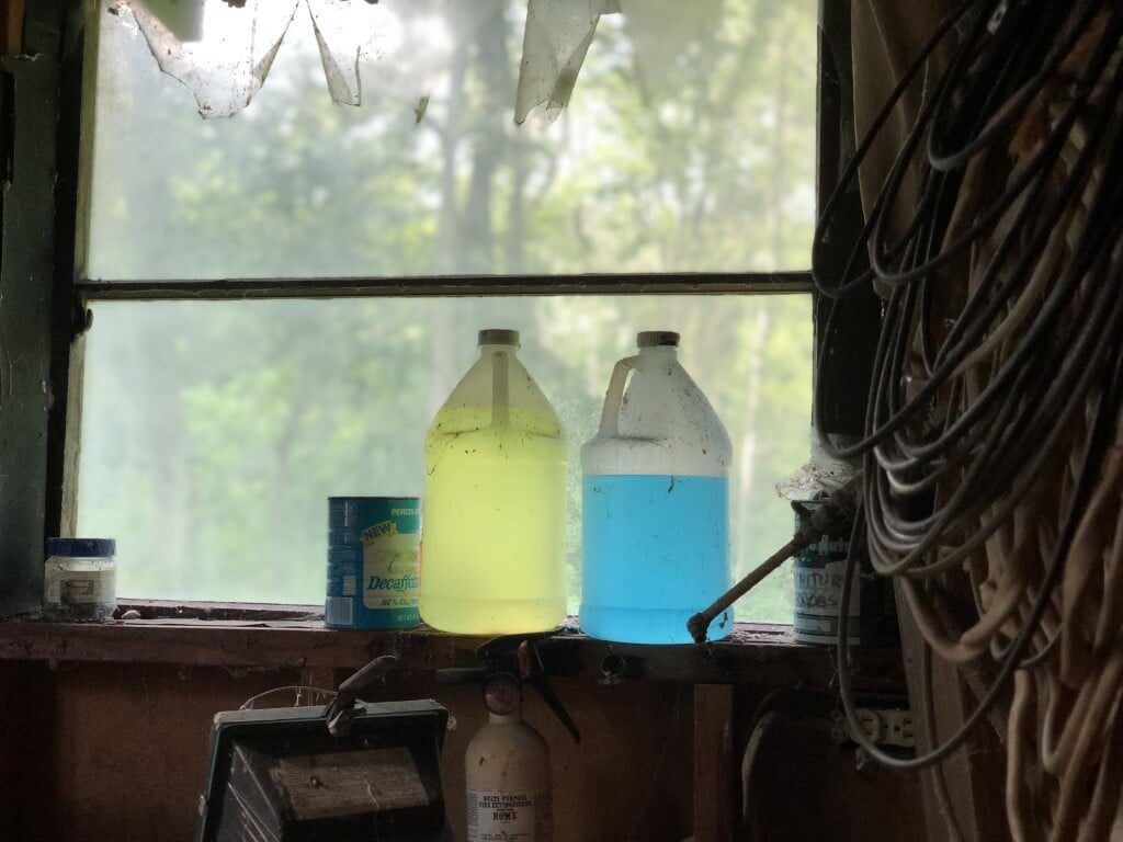 Two jugs of old liquid in a window