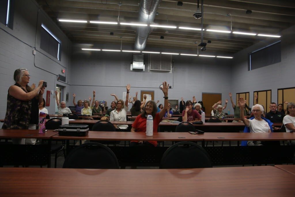 Group of people at tables raising their hands