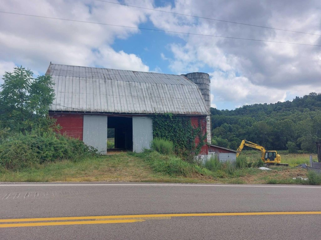 A red barn and yellow backhoe.