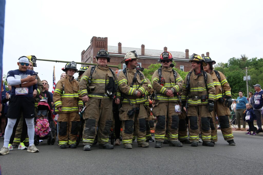 Firefighters in turnout gear line up at the starting line.