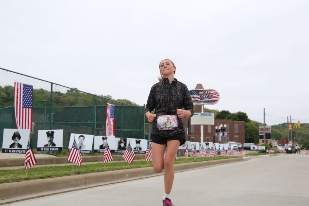 A girl runs past American flags and photos of 9/11 first responders.