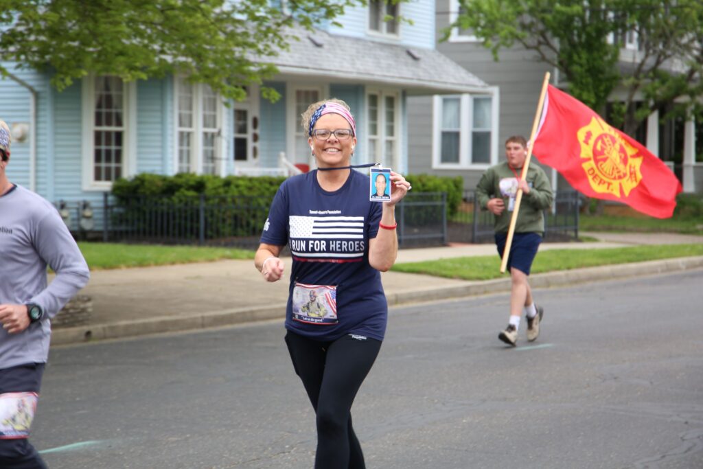 A woman holds up a photo of a 9/11 first responder.