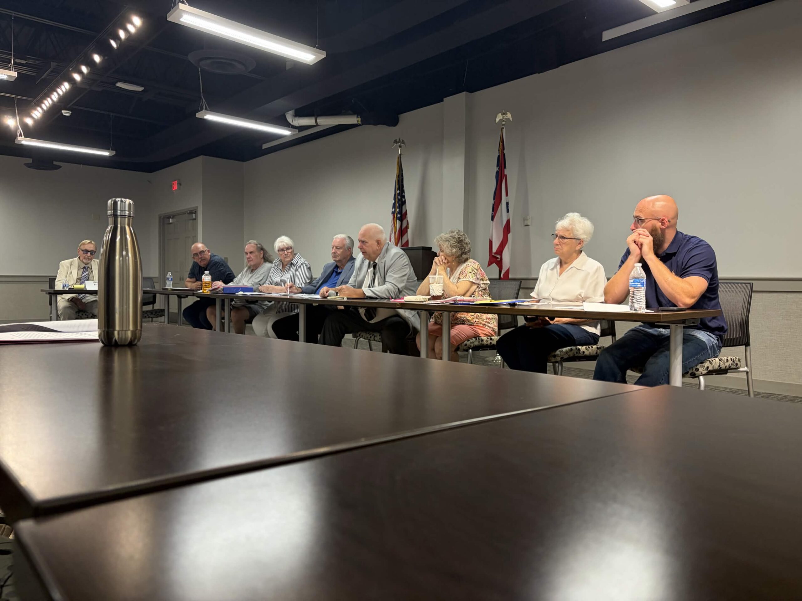 People sitting in a row in front of a large table