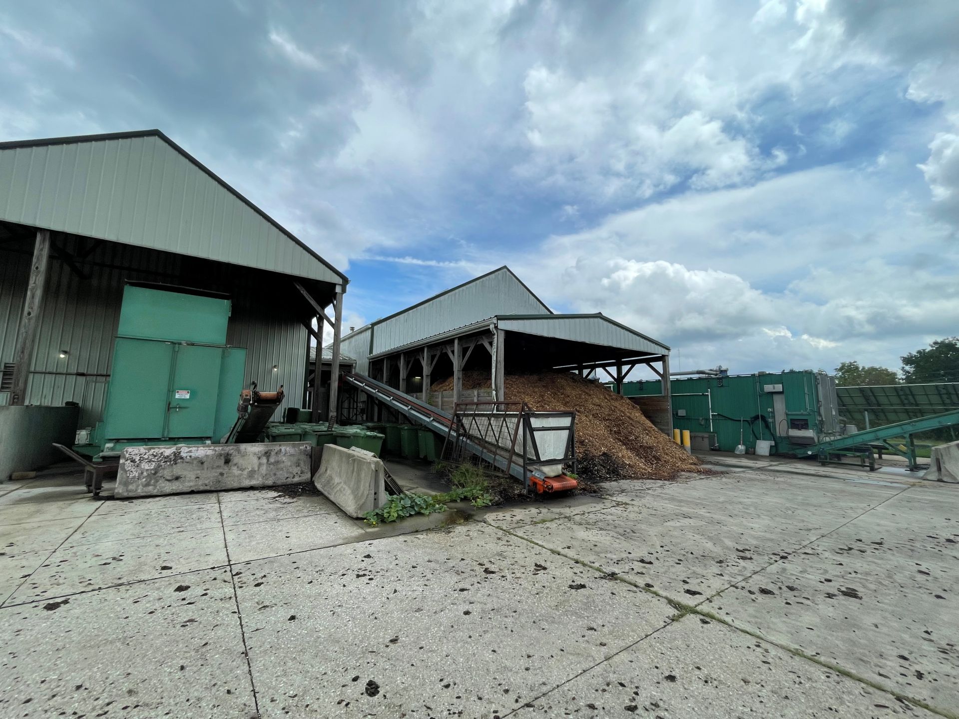Two barns with green composting machines.
