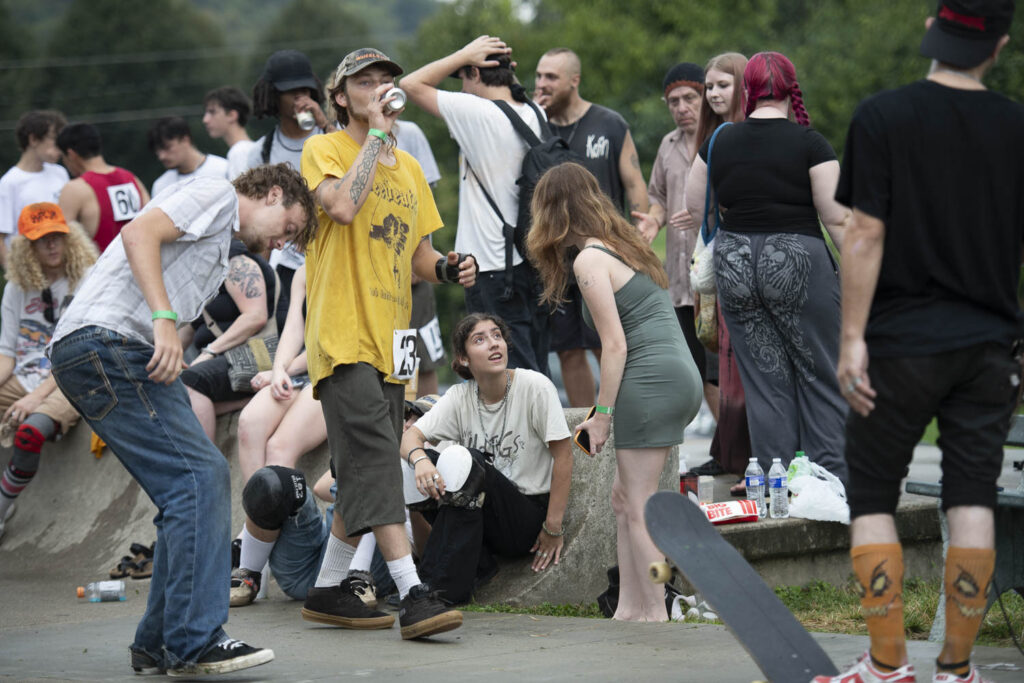 Group of people in skater clothes with skateboards socializing.