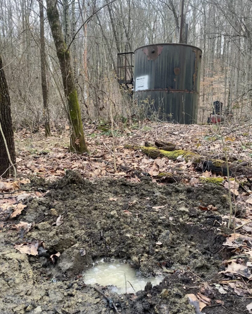 An oil and gas storage tank pictured in the winter woods.