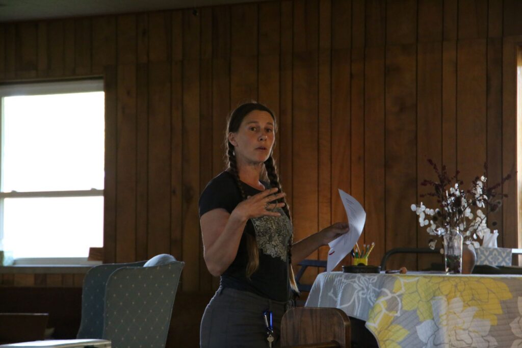 A brunette woman with a paper in hand gestures