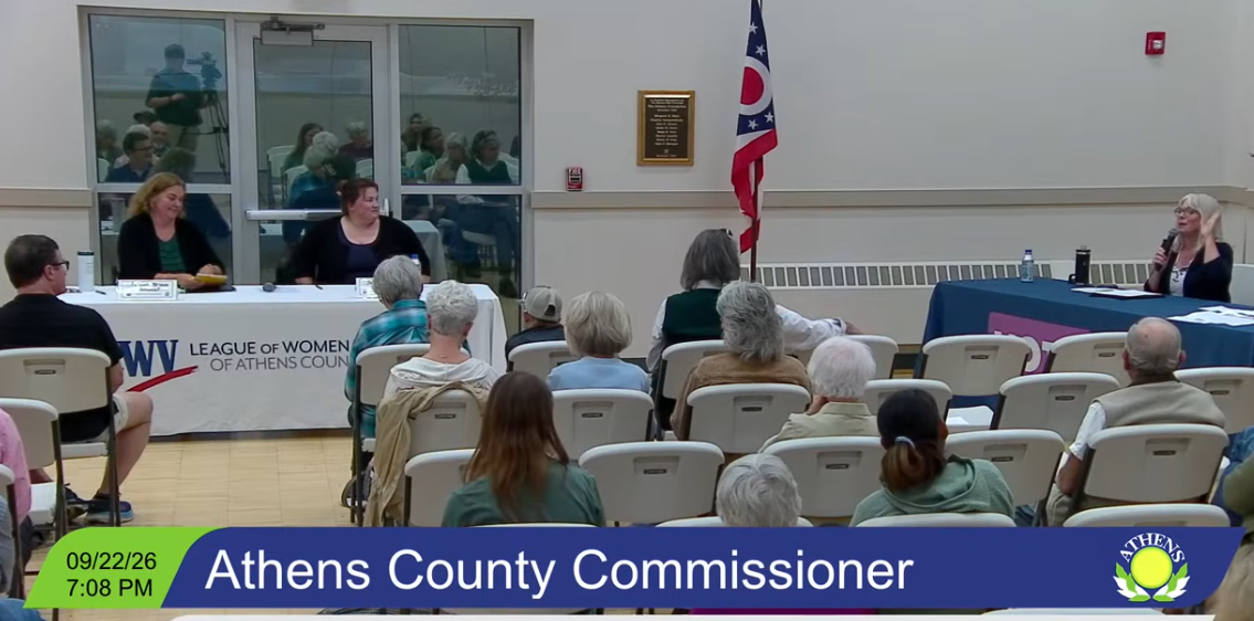 Forum with candidates sitting at table and people in chairs